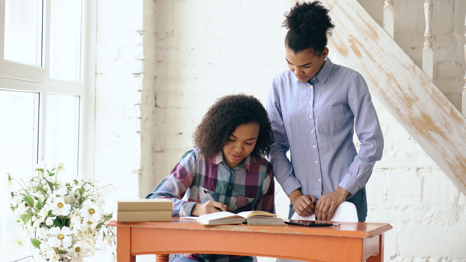 A parent supporting her daughter as she studies at home